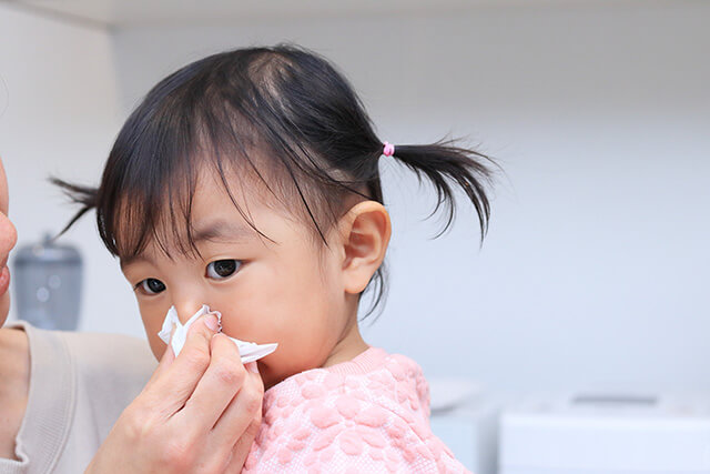 お母さんに鼻を拭いてもらう小さな女の子