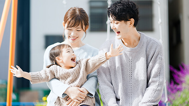 女の子と両親がブランコに座っている様子