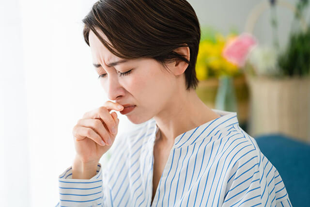 鼻の下に手をあてて苦しそうな女性