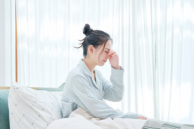 眉間に手をあてる女性